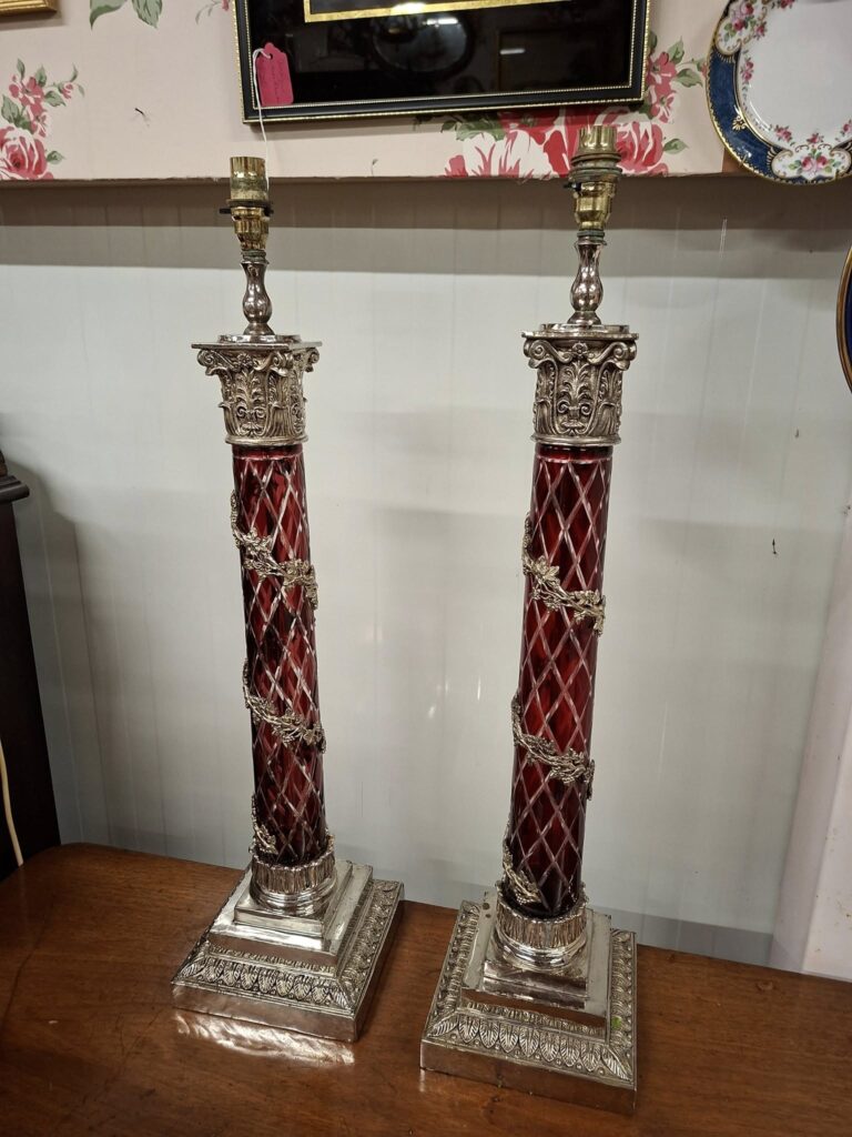 Pair of Ruby Cut to Clear Glass Bohemian
Table Lamps. Corinthian Column Silver Plated
on Copper With Trailing Vine Detail. In very good condition both working. Measure 27" high on 6.75" square base.