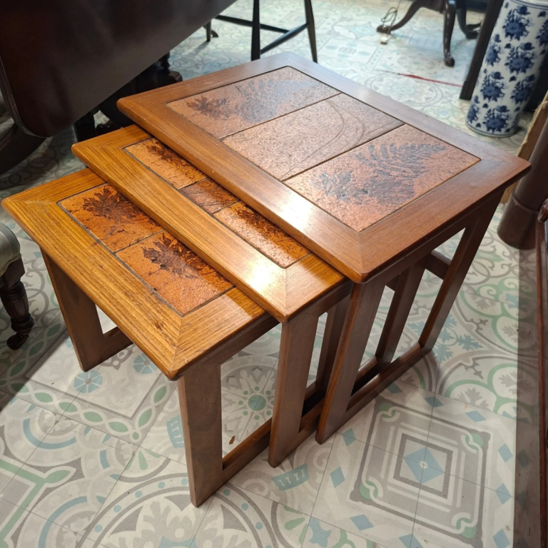 1960s Set of three teak  tables with decorative 
Tile inset. From Keith Eatwell, English Manufacture  of Mid-Century Furniture.  
Measurements: Large 23" wide by 17" by 19" high.
Middle: 20 wide by 16" by18" high.
Small: 16" wide by 16" by 16" high. All in excellent condition.